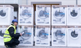 Installatör på huk framför Electrolux tvättmaskiner