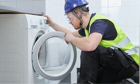 Installatör som tittar in i tvättmaskin
